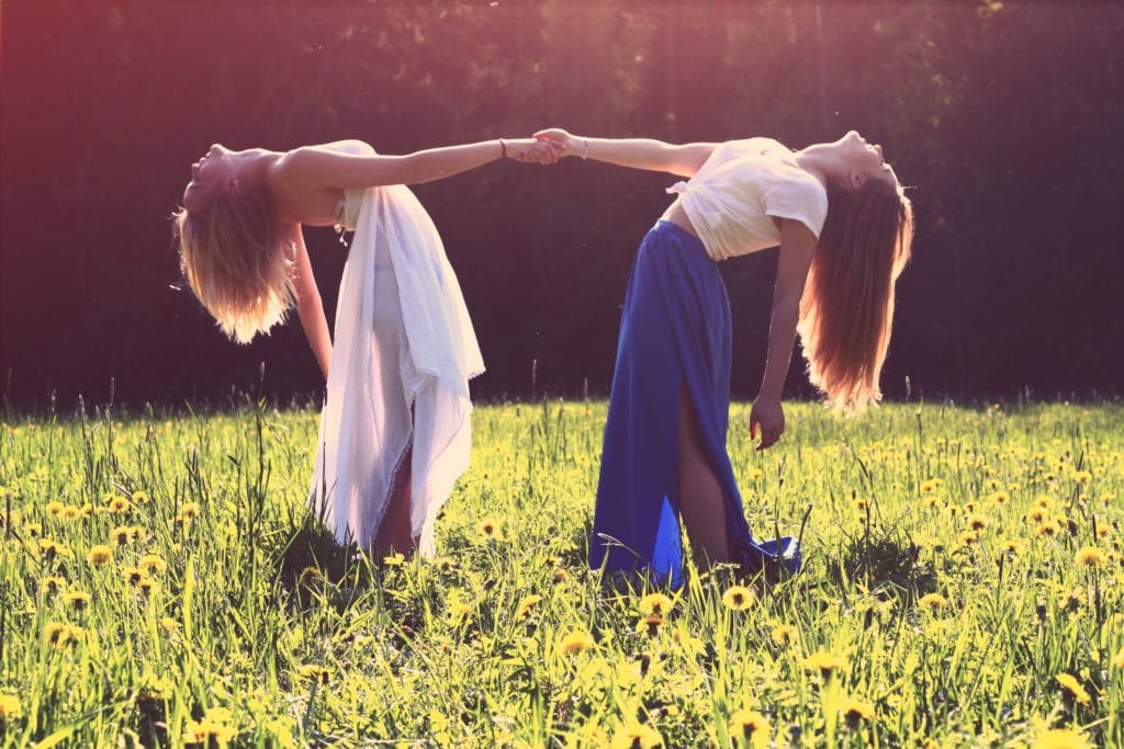 two women dancing in a field during summer