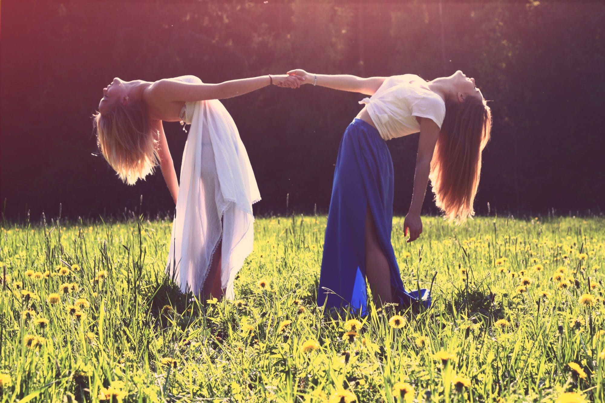 two women dancing in a field during summer