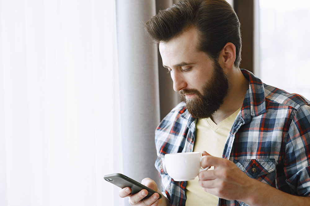 man with full beard and hair reading a text message