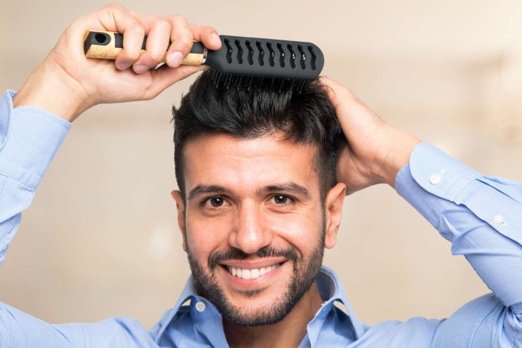 Hombre con cabello denso y sano usando un peine - Dr. Panno